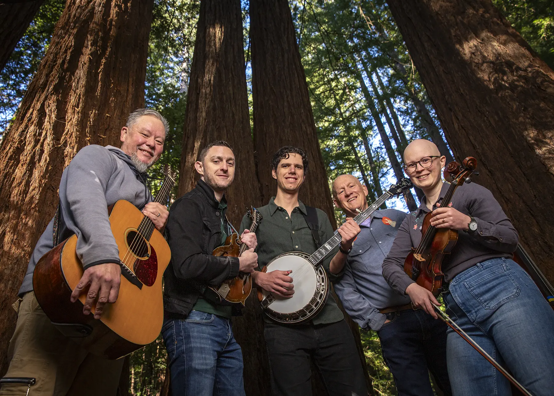 Critical Grass bluegrass band posing for a photo outside among tall redwood trees