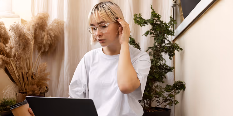 A woman on a computer with her hand held to her head