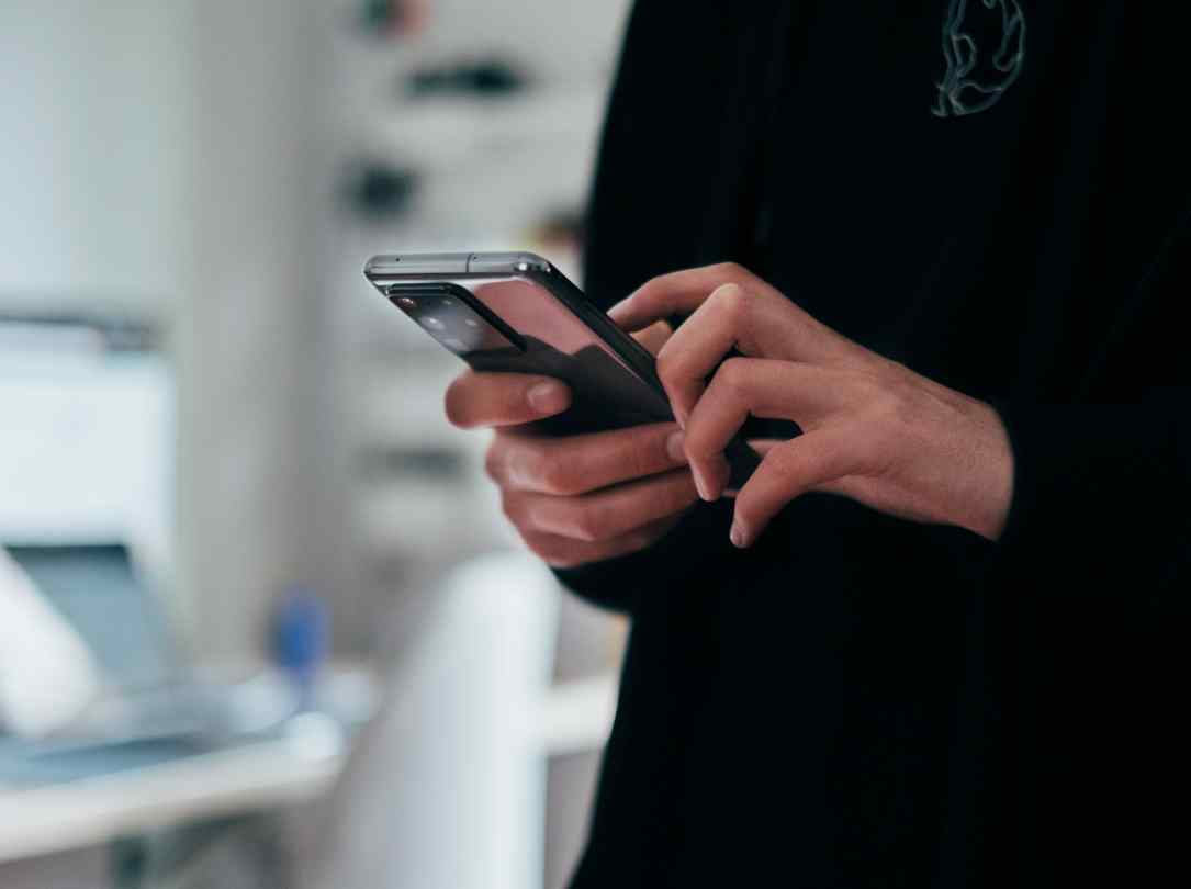 Uma pessoa segura o smartphone lendo algo na tela.