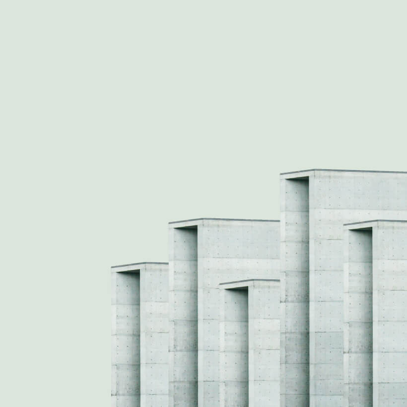 Minimalist architectural image of staggered white concrete building sections against a pale sky.