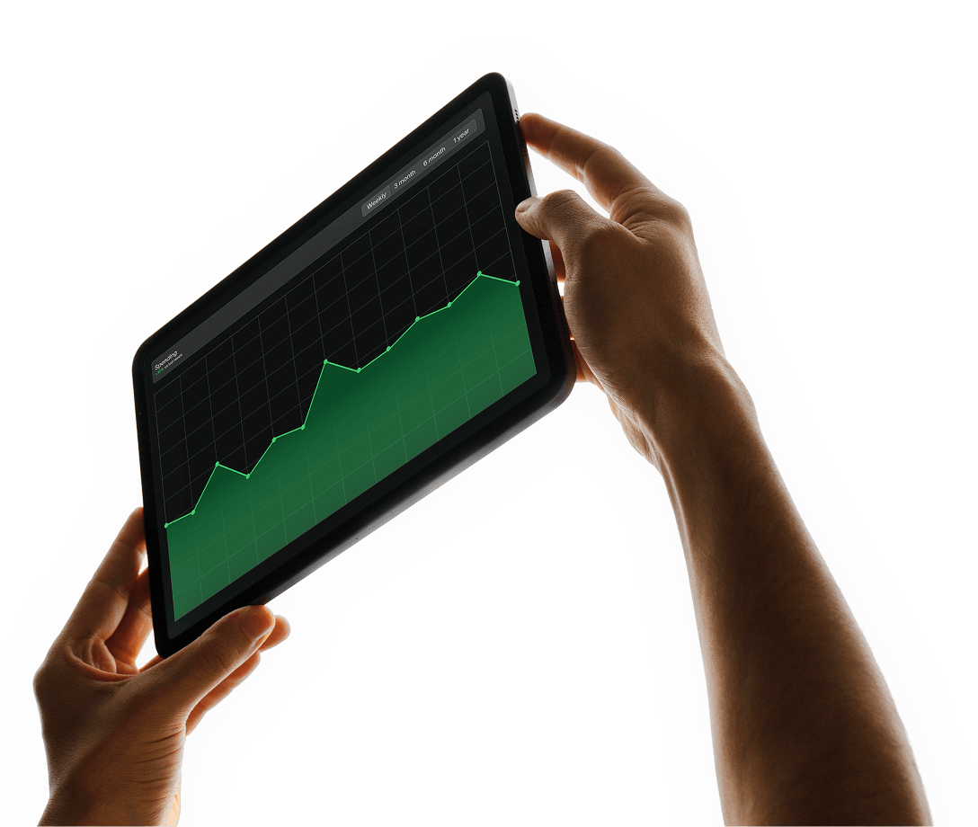 Hands holding a tablet showing a green line graph trending upward on a black background.