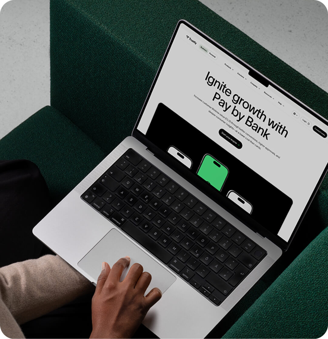 Person using a laptop with a website titled 'Ignite growth with Pay by Bank' displayed on the screen.