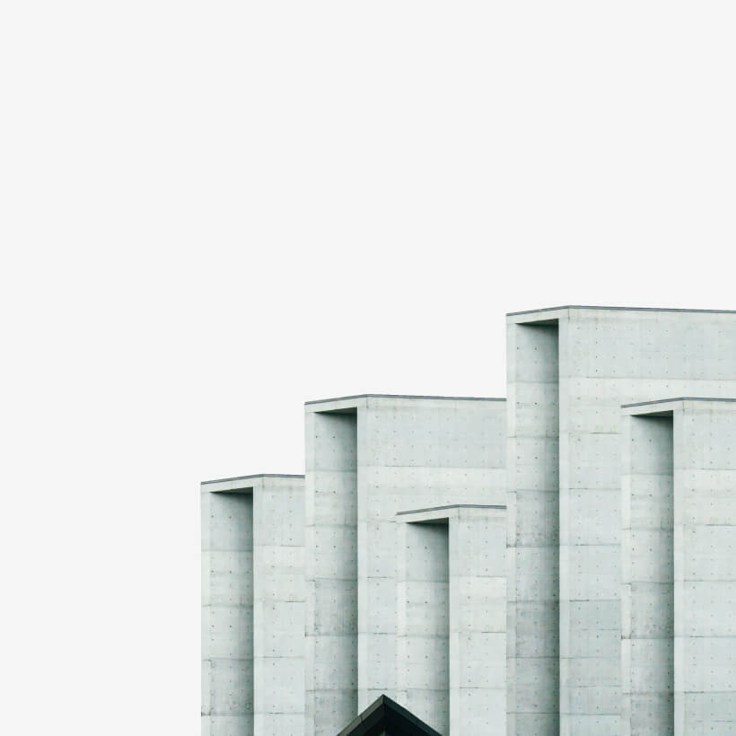 Minimalist concrete building with multiple rectangular vertical sections against a plain sky.