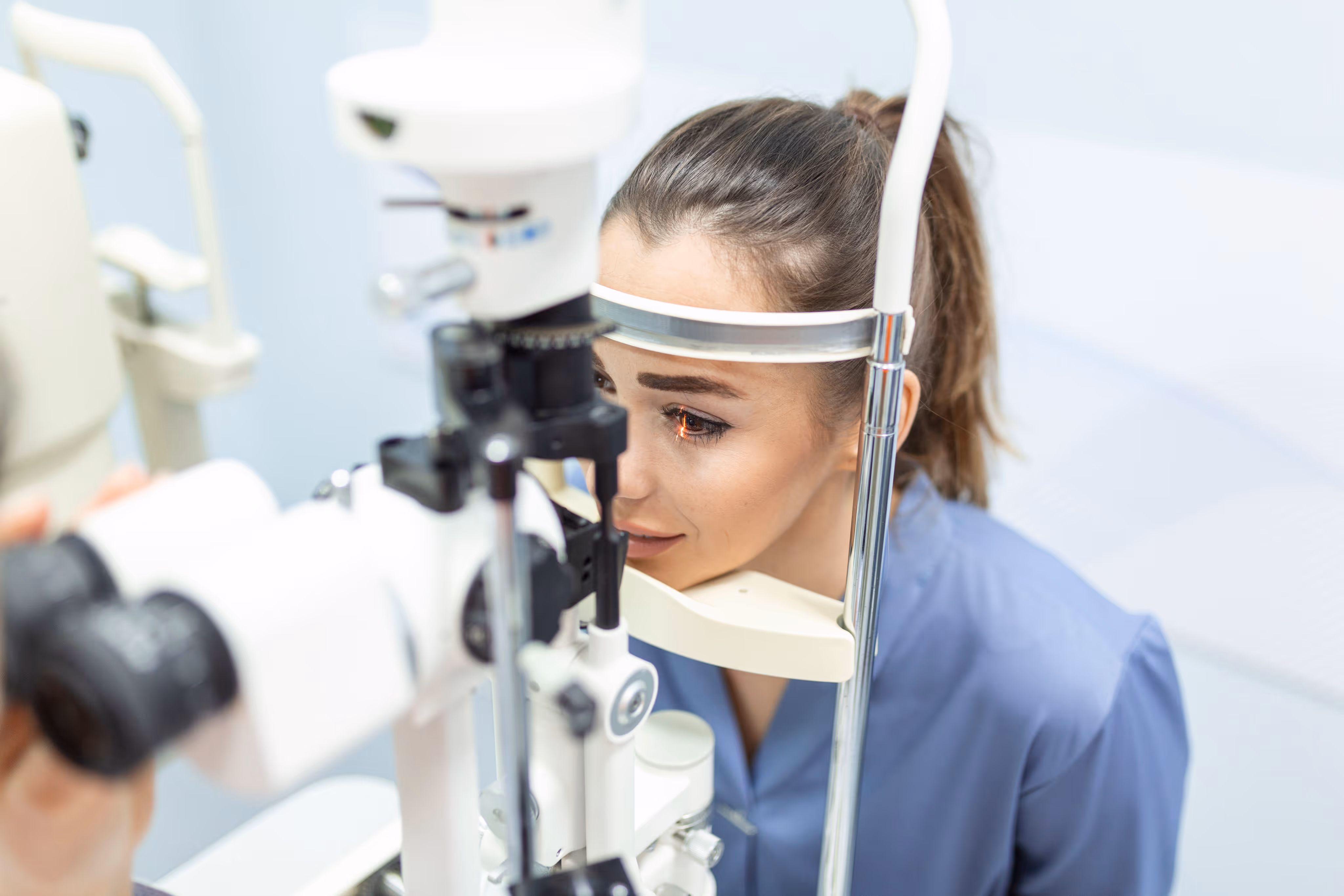 Woman undergoing an eye exam using a slit lamp in an eye clinic.