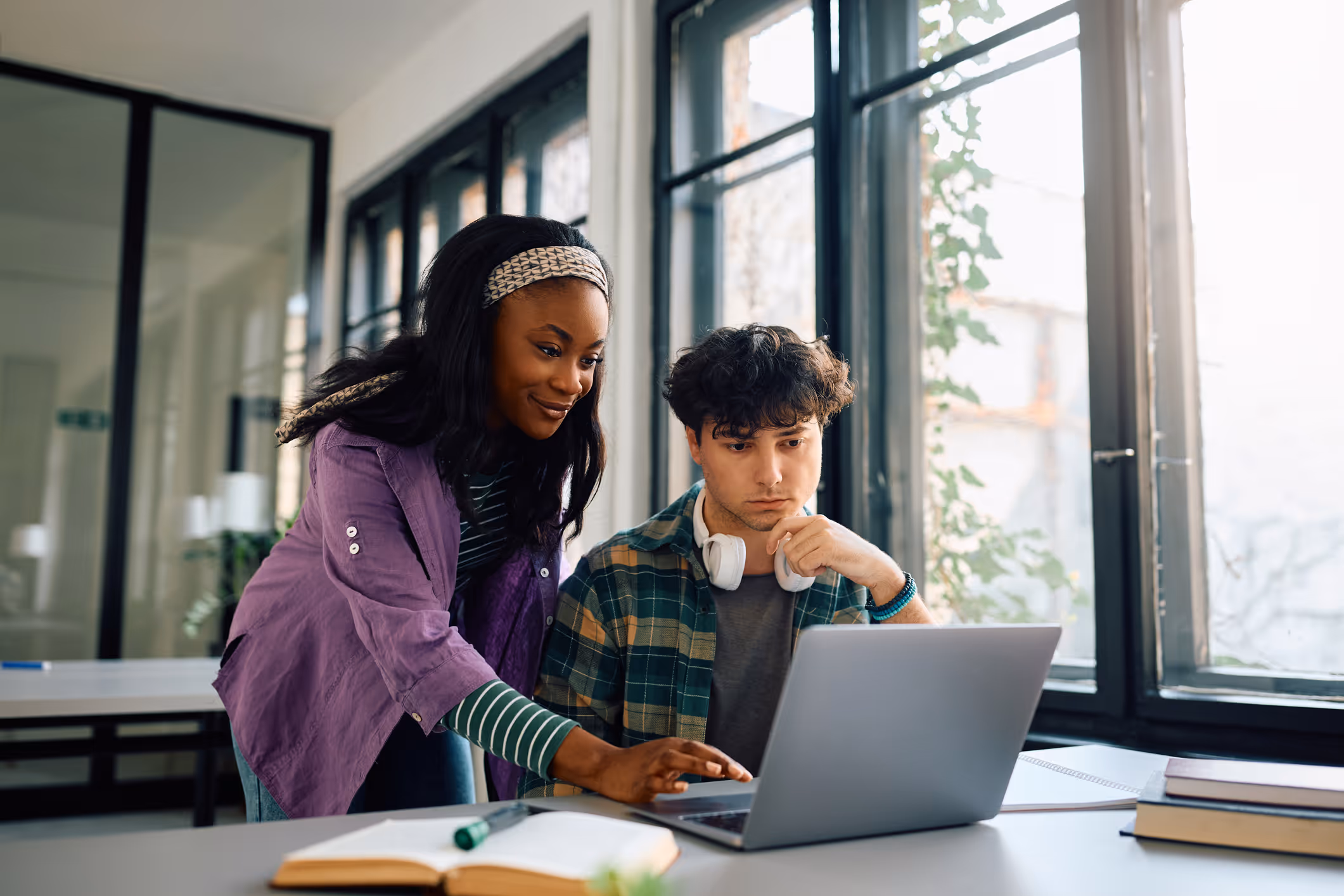 A professional educational psychologist provides academic test support to a teenage student on a laptop.