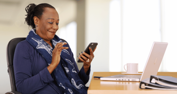 Local government finance employee verifying a sign-in on her smartphone at her desk