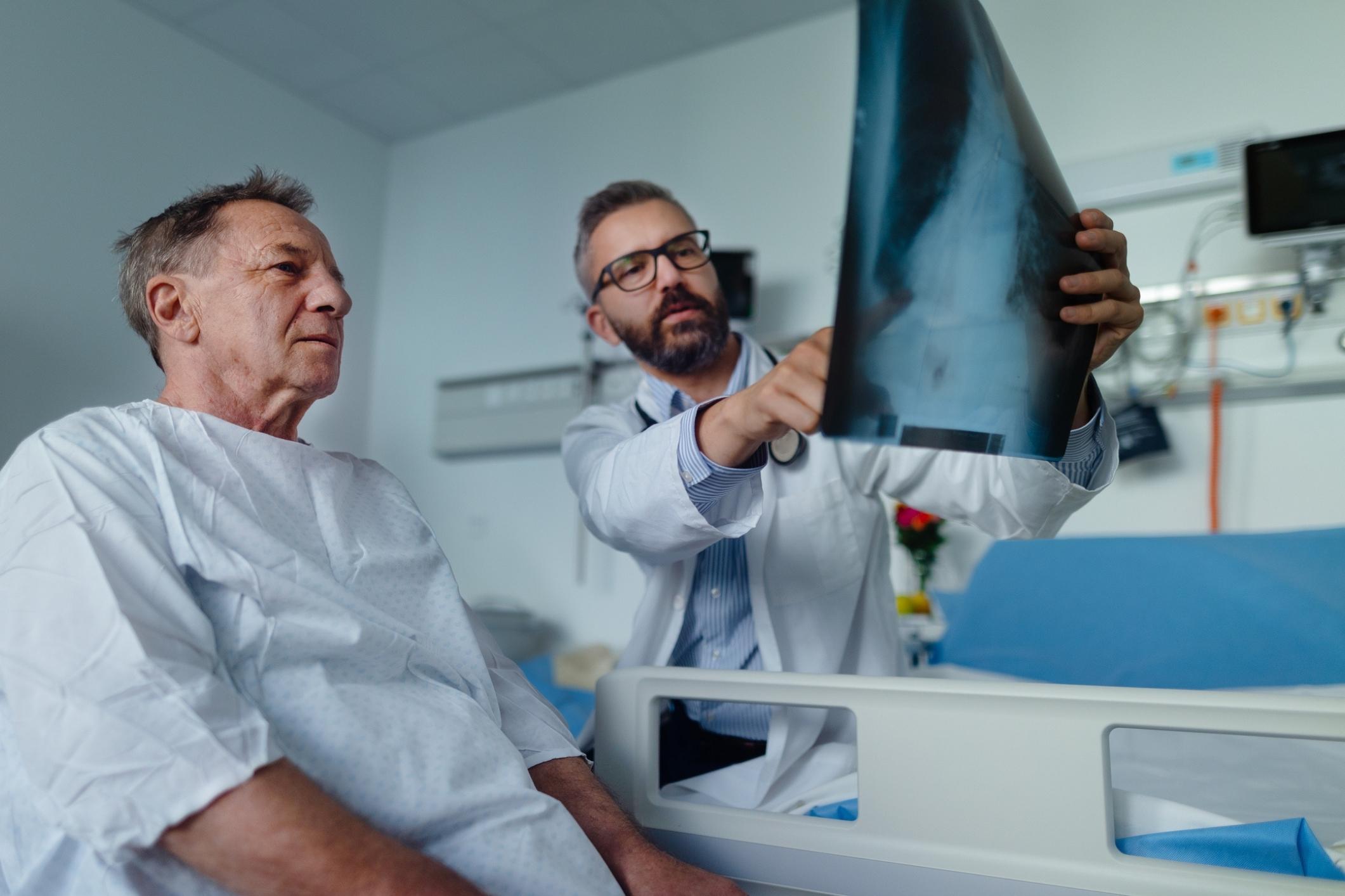 A man reviews a lung x-ray with his doctor. Asbestosis lawsuit settlements can help him pay for medical bills.