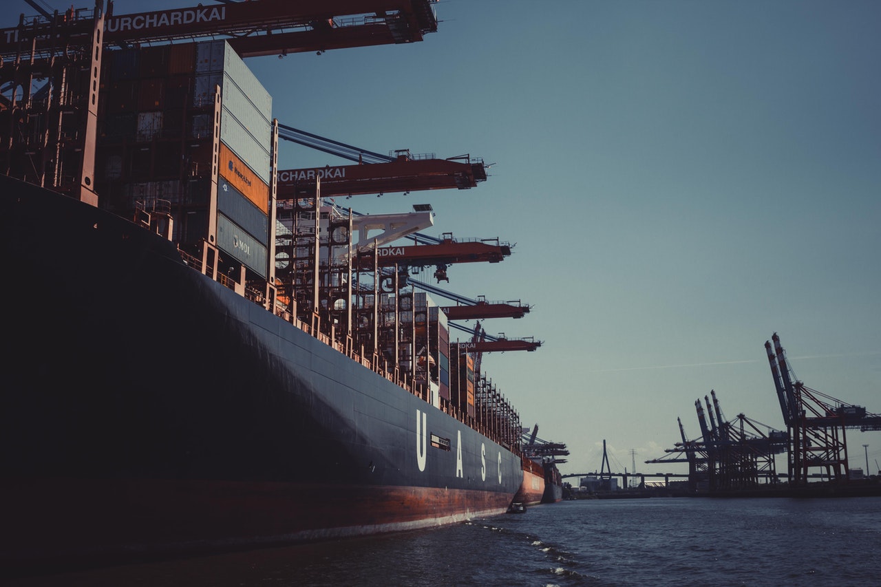 A container ship at a shipyard with cranes overhead moving shipping containers