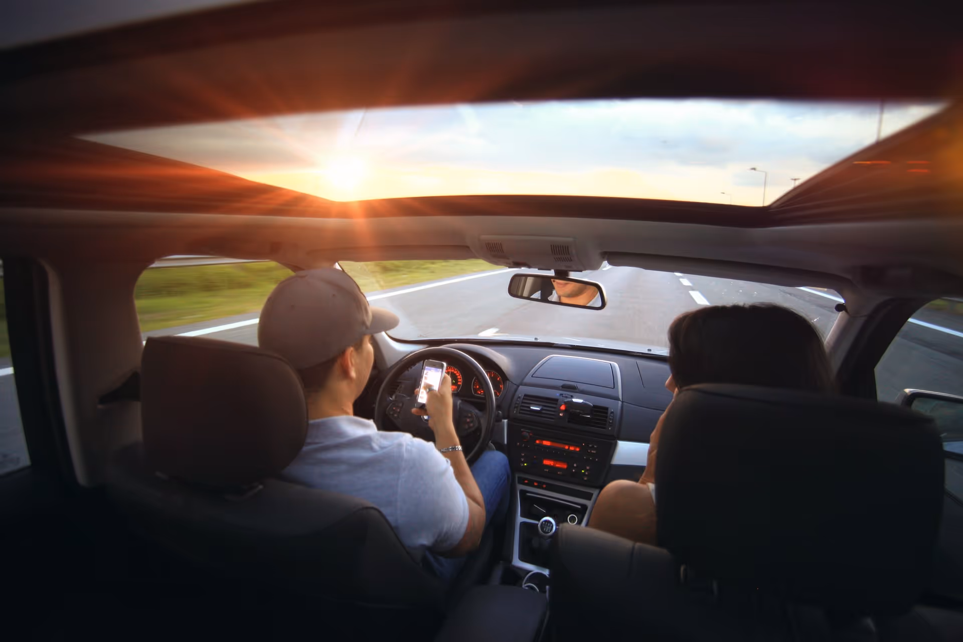 man driving a car at sunset
