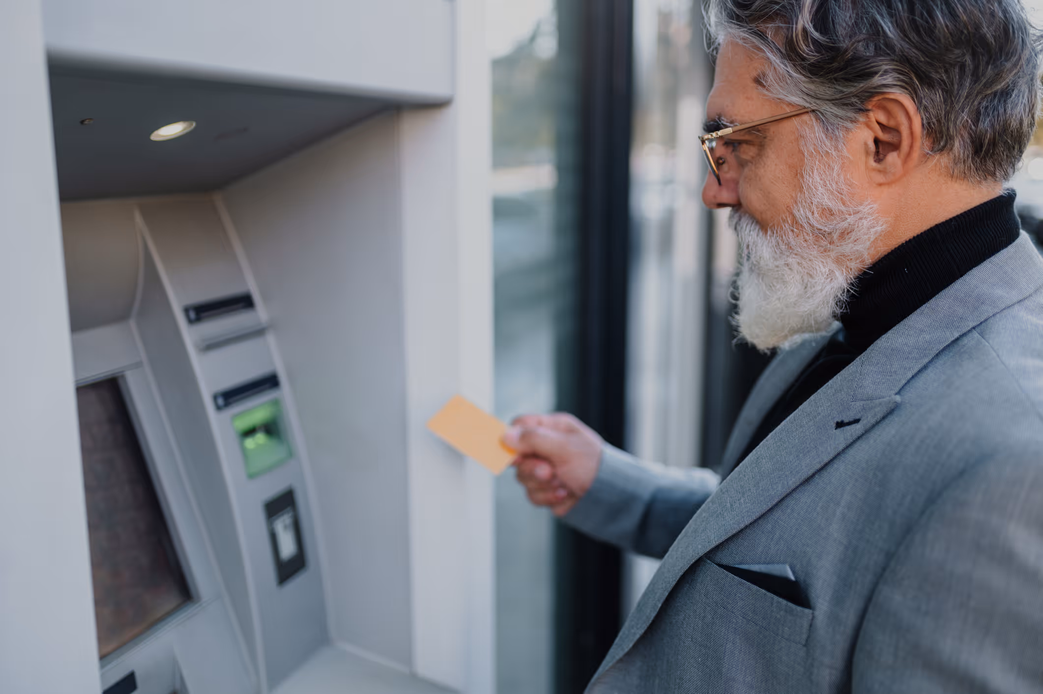 A man in a gray suit using an ATM