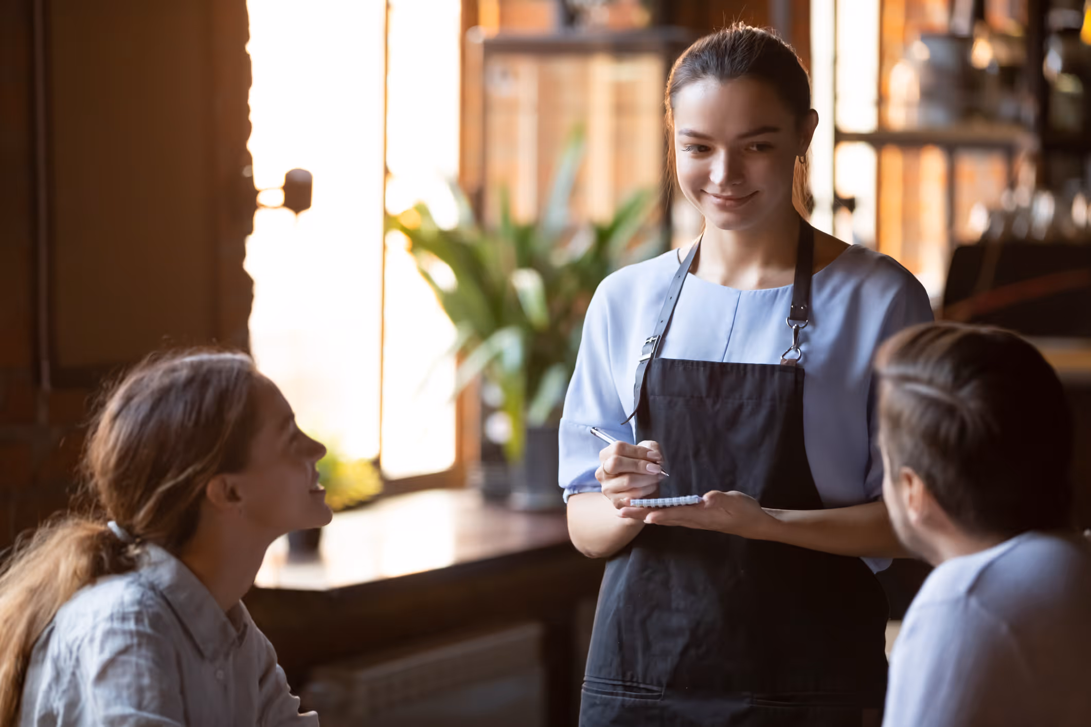 A waitress in a restaurant takes a married couple’s order.