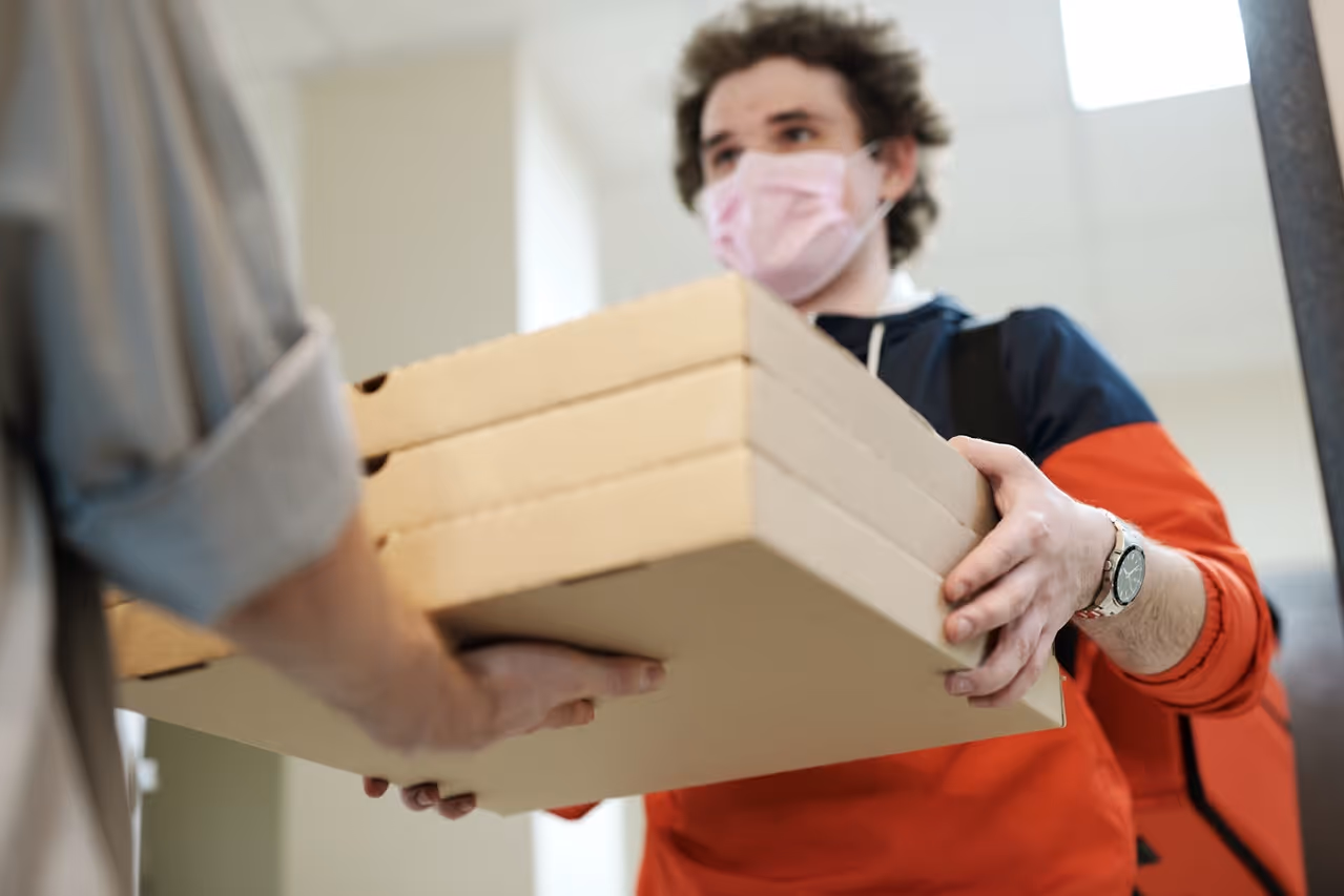Pizza delivery man handing three pizza boxes to a customer