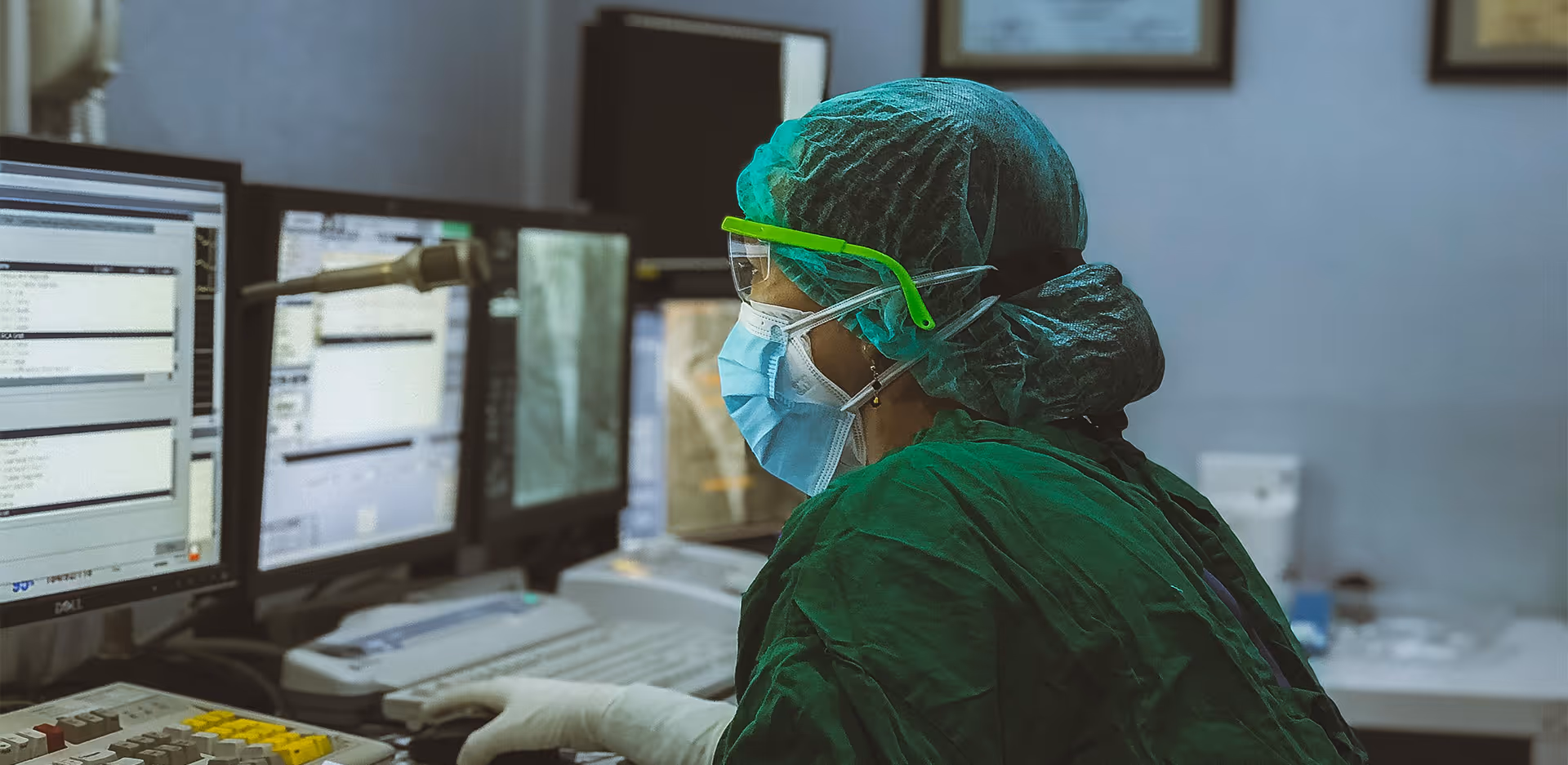 A lab technician in protective garb sitting at a computer