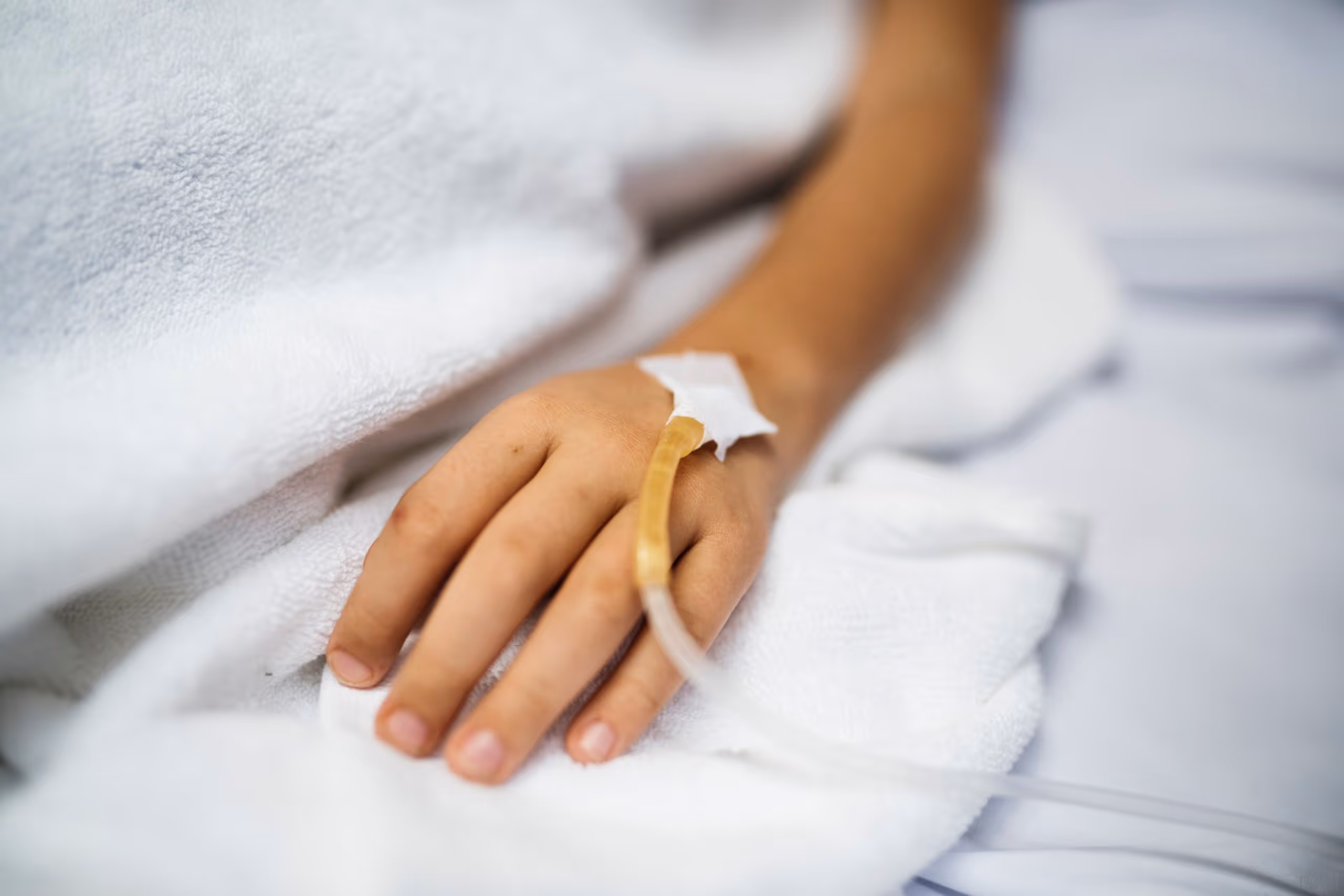 IV in the hand of a patient in a hospital bed