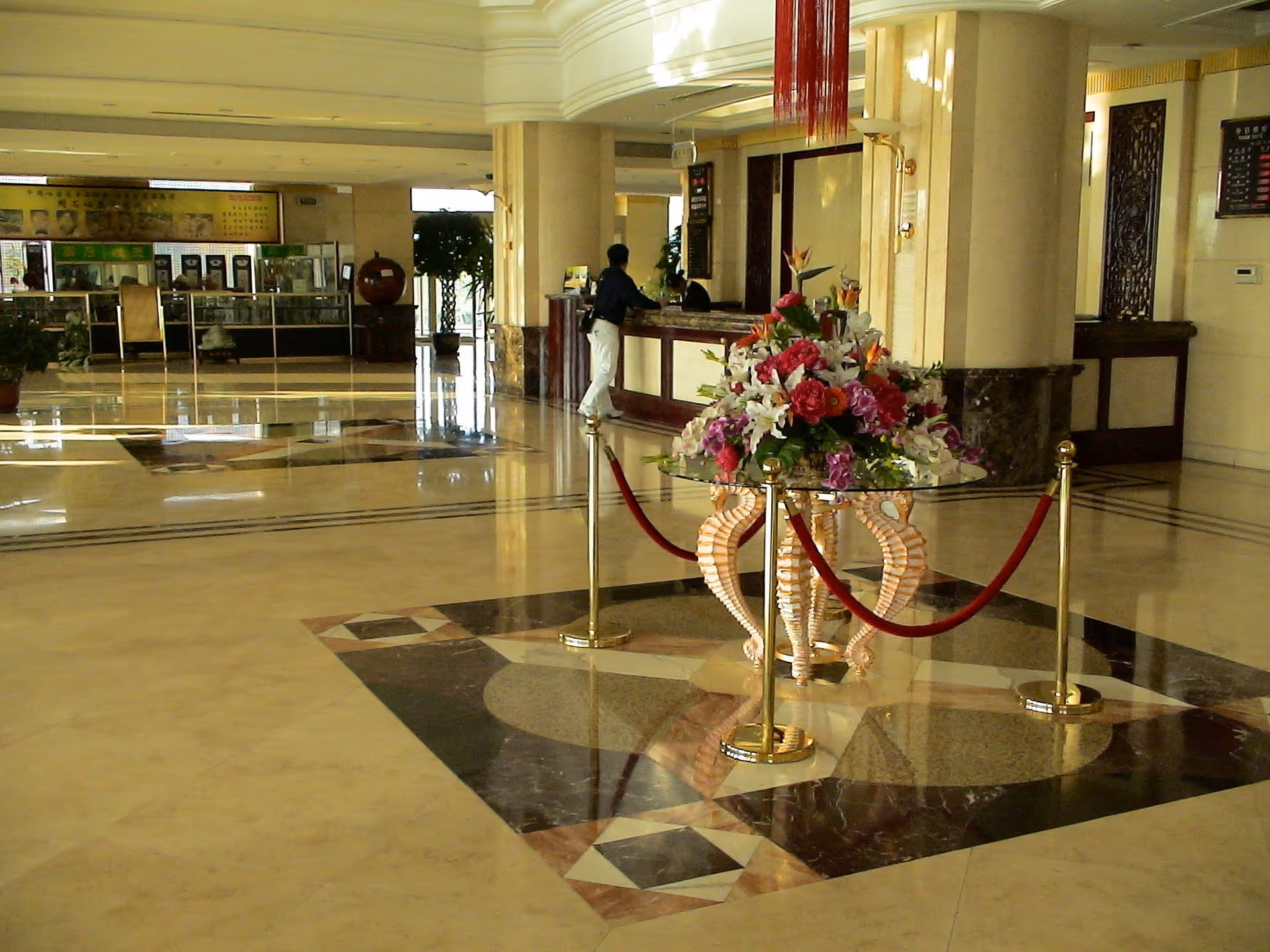 A man standing at the reception desk in a hotel lobby