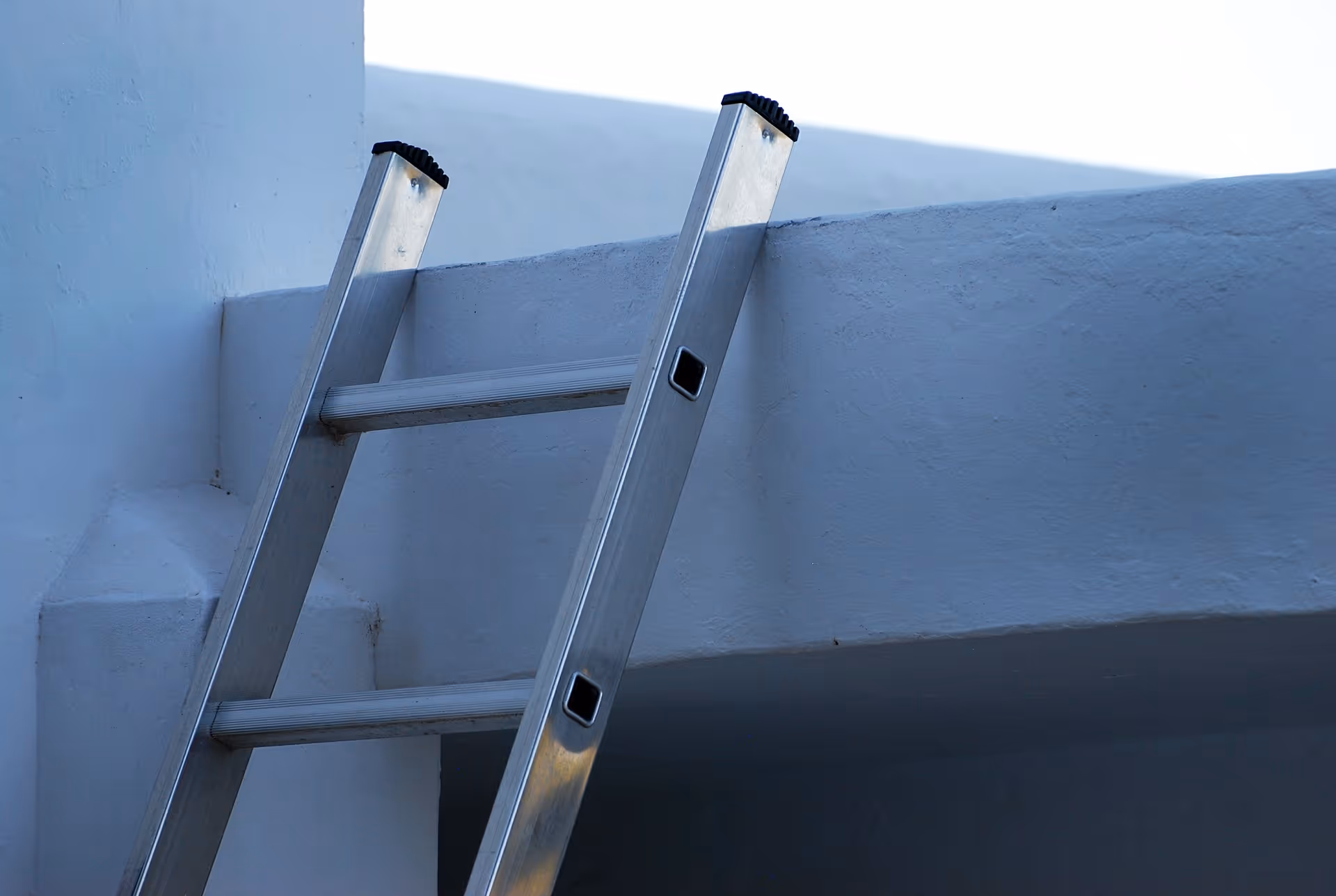 An aluminum ladder leaning up against a wall