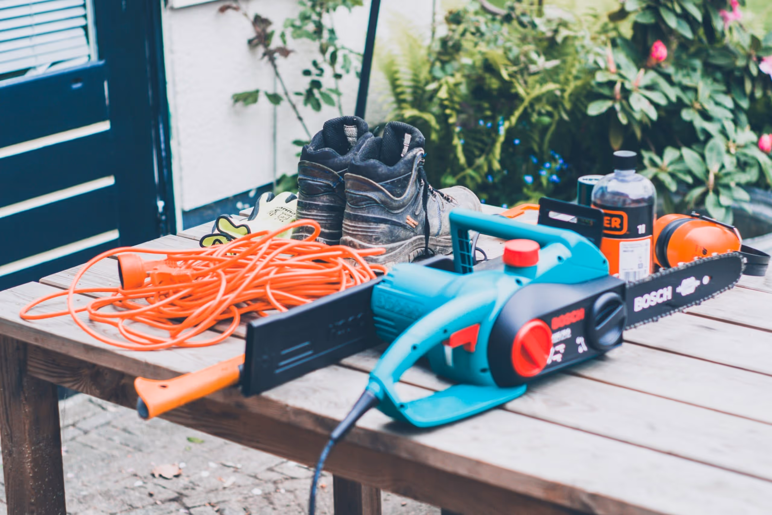 A pair of boots, extension cord, chainsaw and other tree care equipment