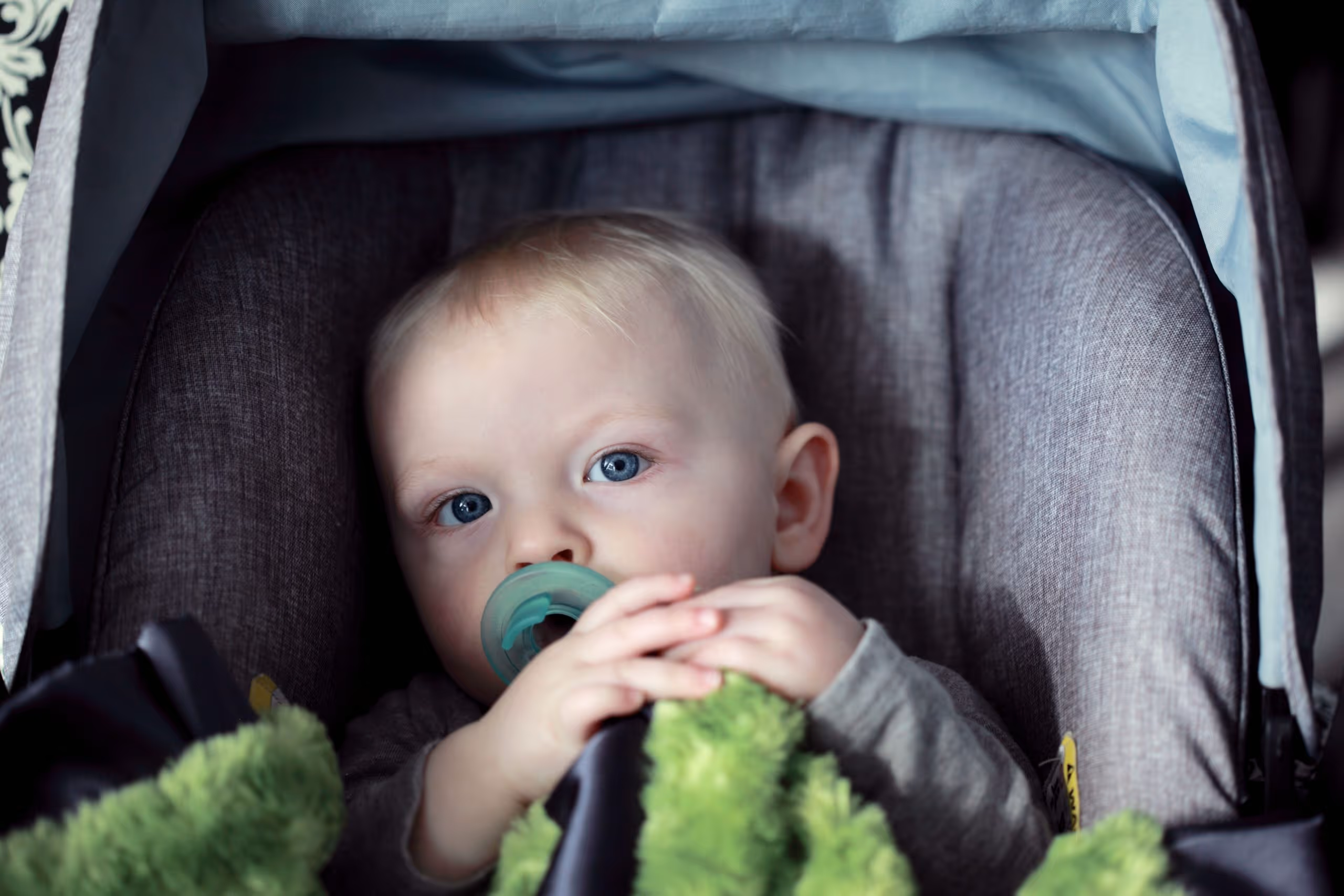 child sucking on a pacifier in car seat
