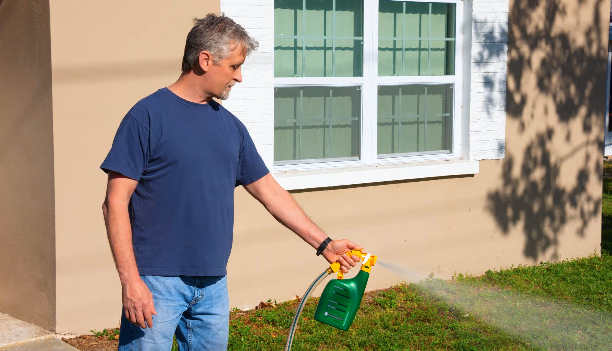 An older man tends to his lawn with Roundup weed spray, unaware that it is toxic.