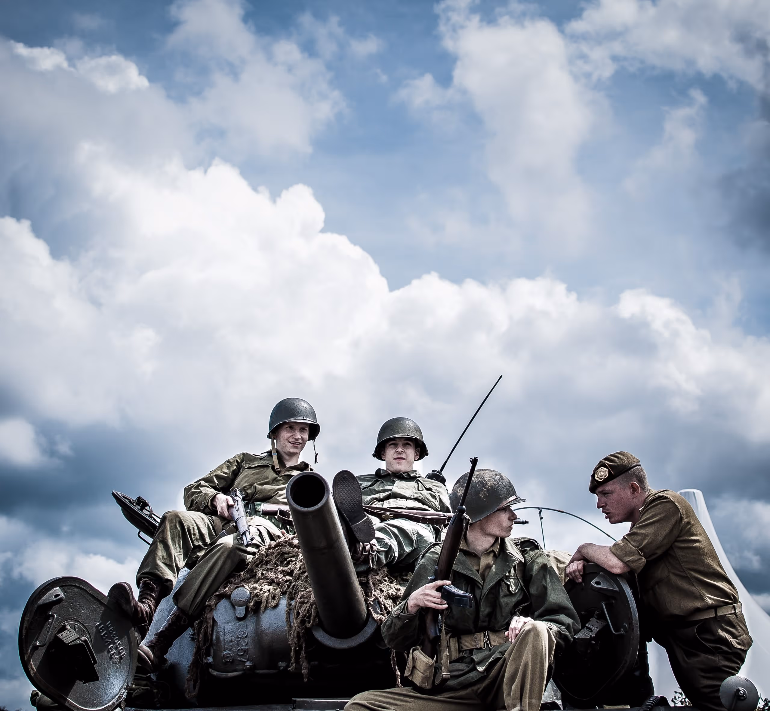 Several soldiers shown riding on a tank