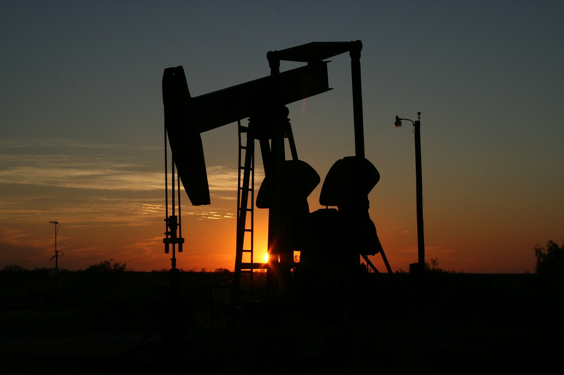 An oil derrick and other fracking equipment seen at sunset