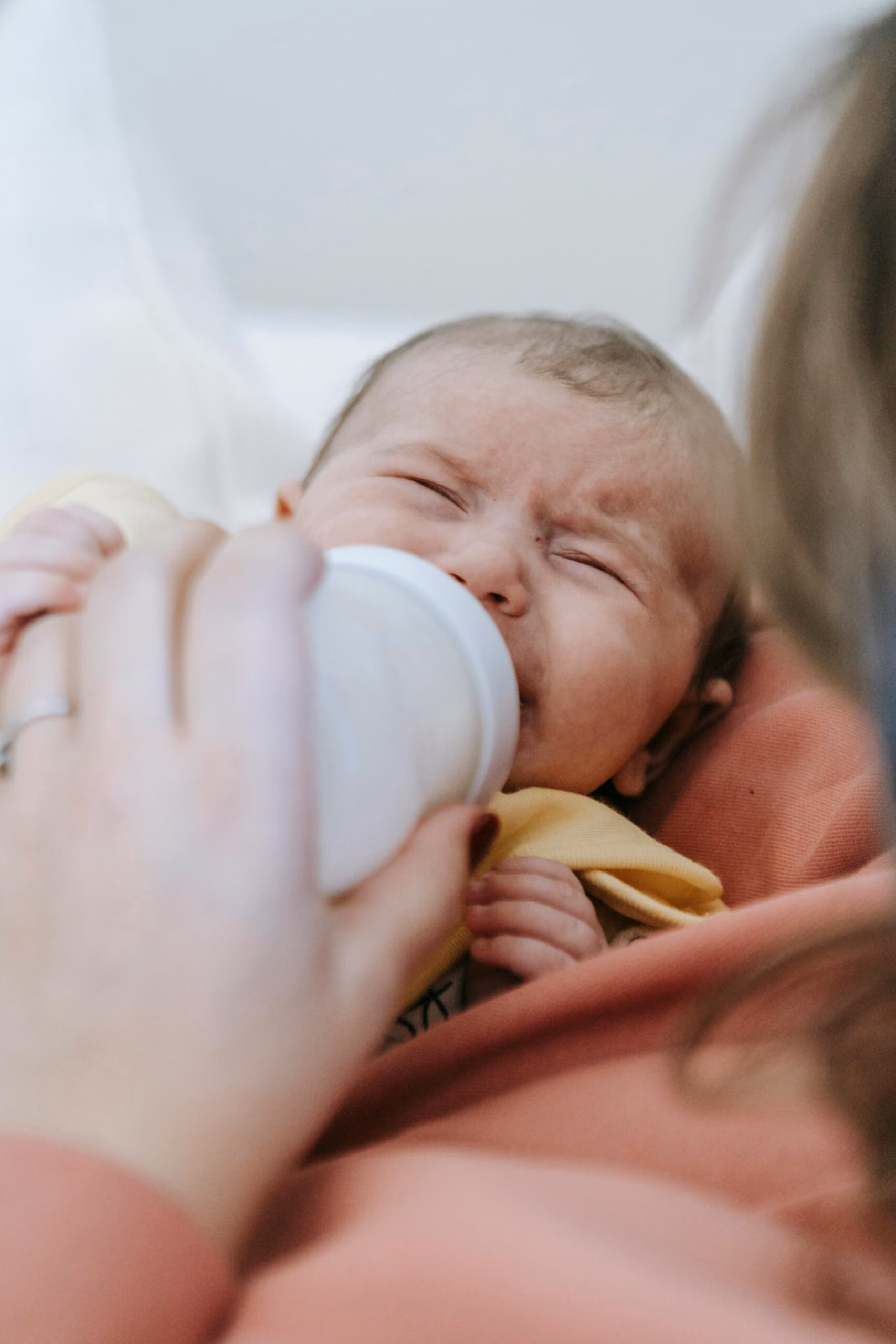 Baby crying, being fed with a bottle of baby formula