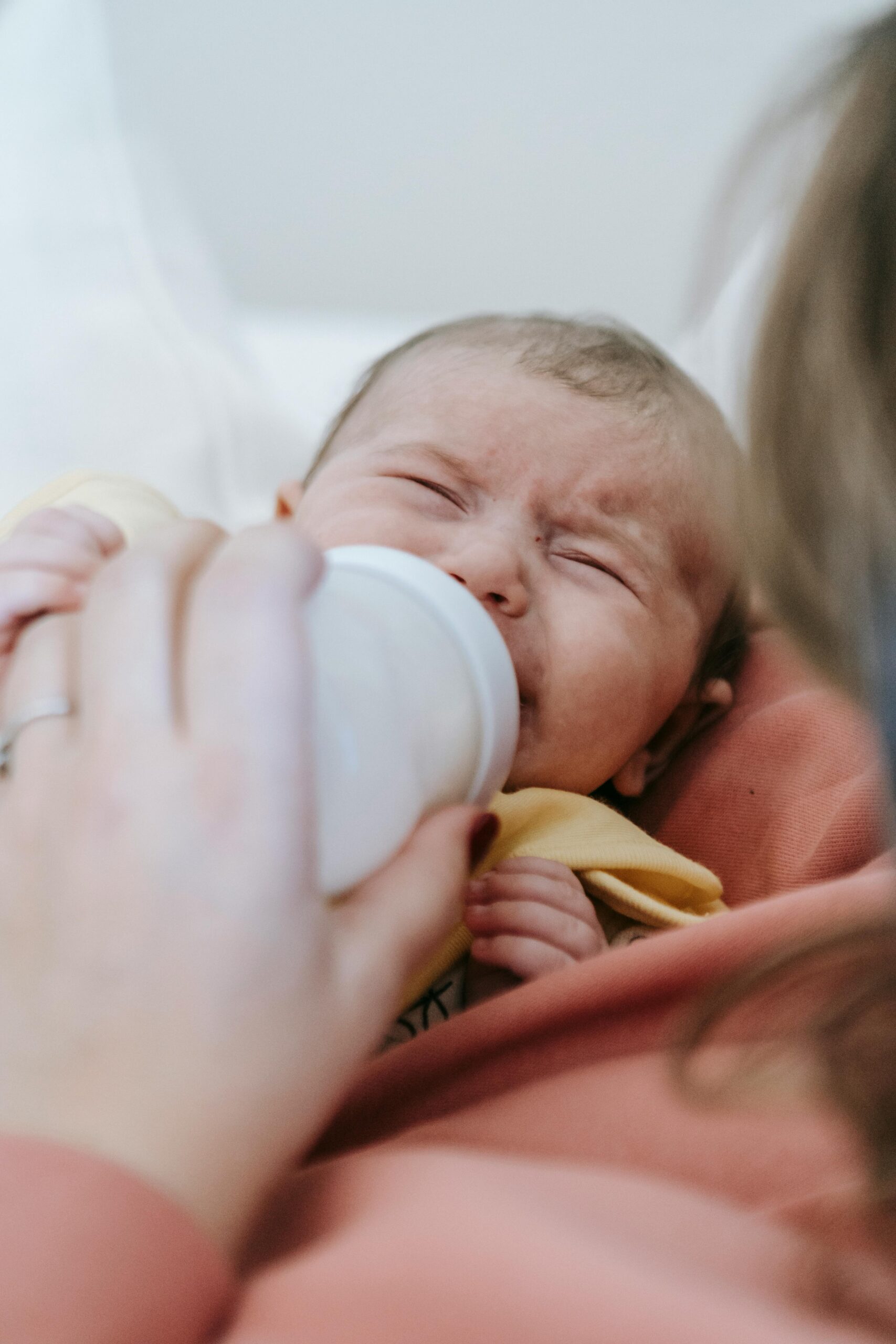 Baby crying, being fed with a bottle of baby formula