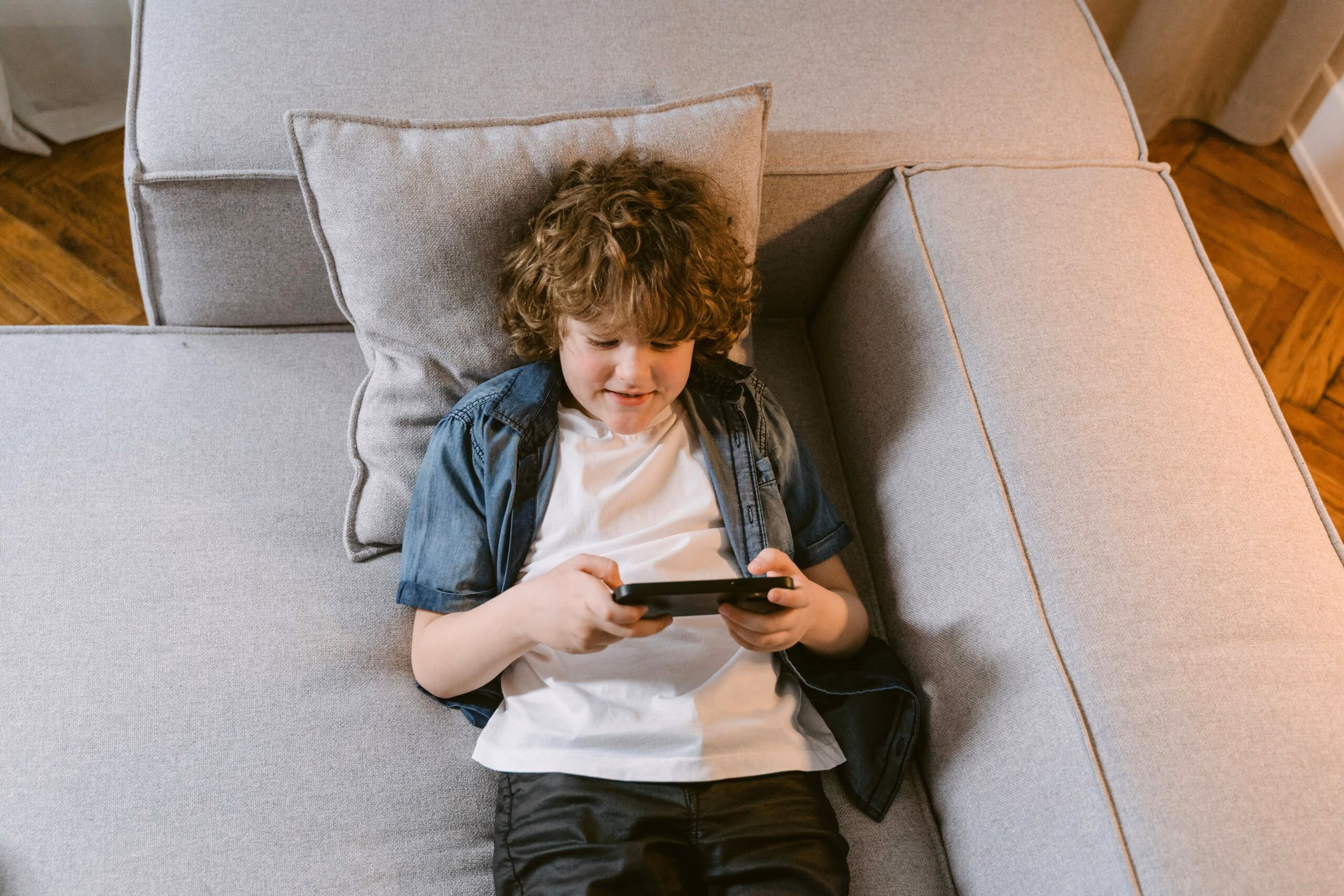 an adolescent boy laying on a bed and gaming
