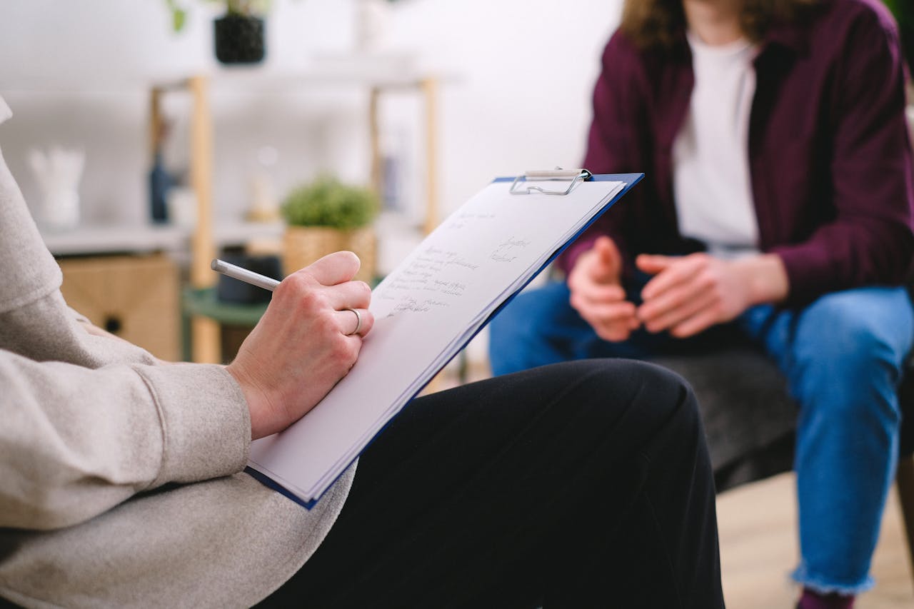 a therapist takes notes whilst talking with a patient