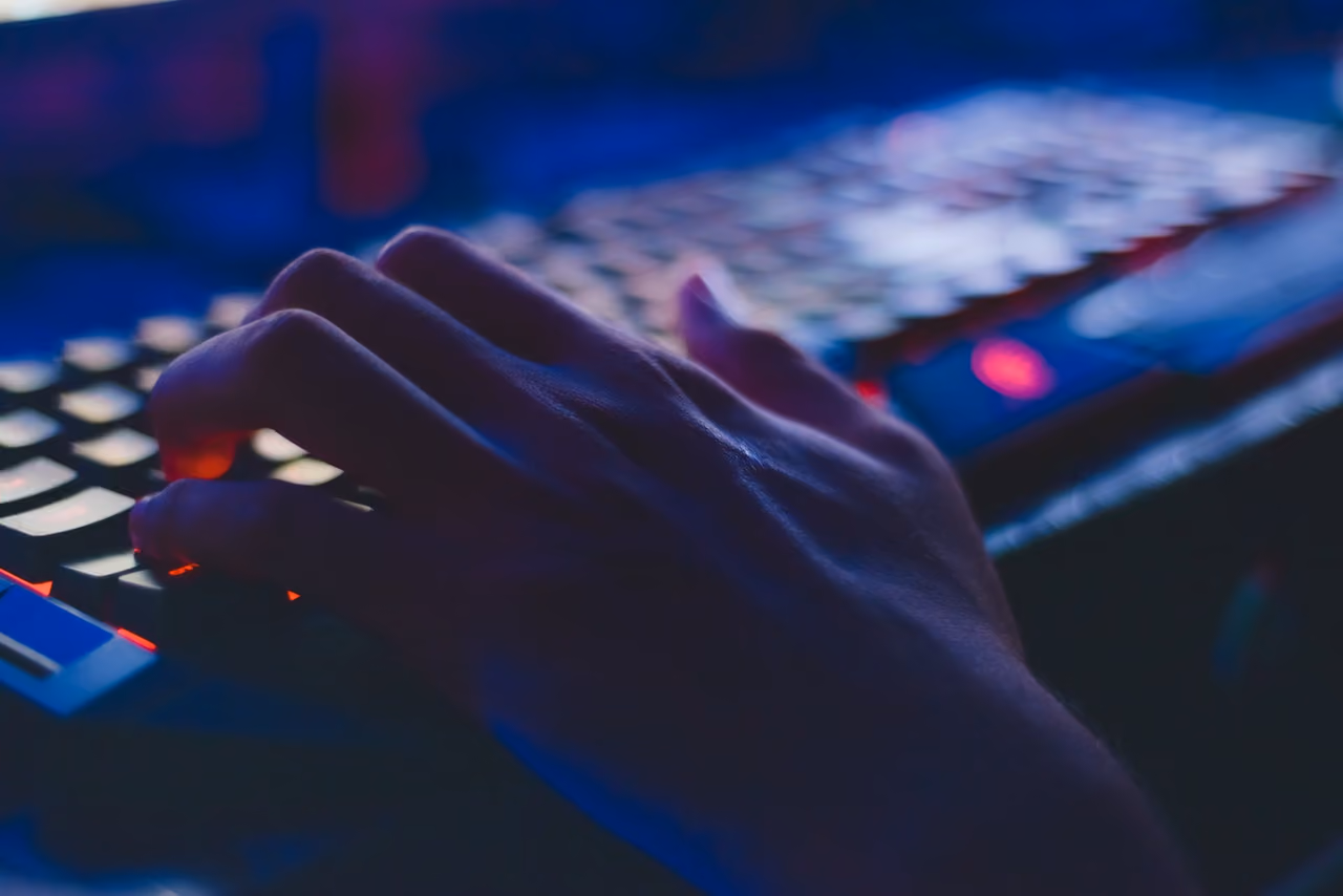 Hand seen typing on keyboard in a dark room