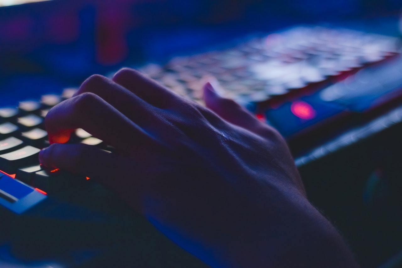 Hand seen typing on keyboard in a dark room