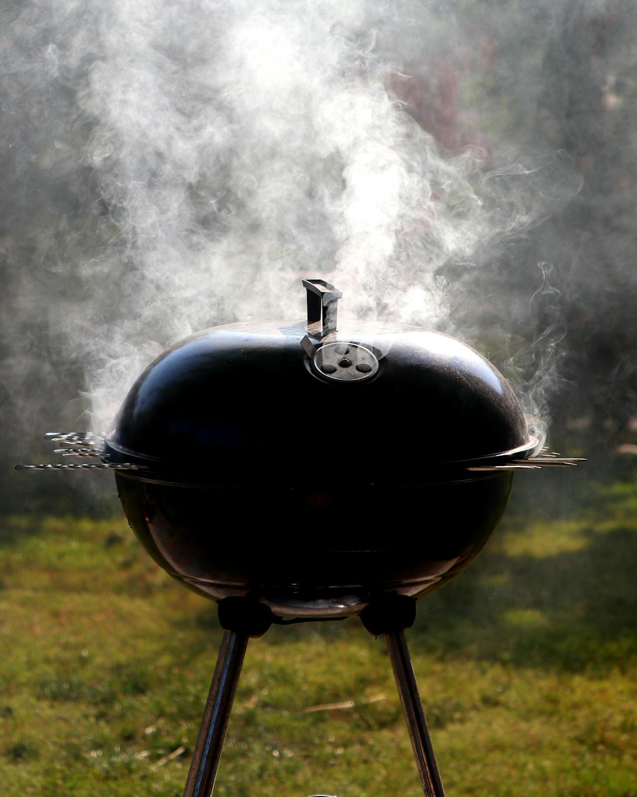 A Weber grill emitting smoke