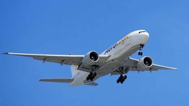 Passagierflugzeug der Fluggesellschaft Aero Logic mit eingefahrenem Fahrwerk im Landeanflug vor blauem Himmel.