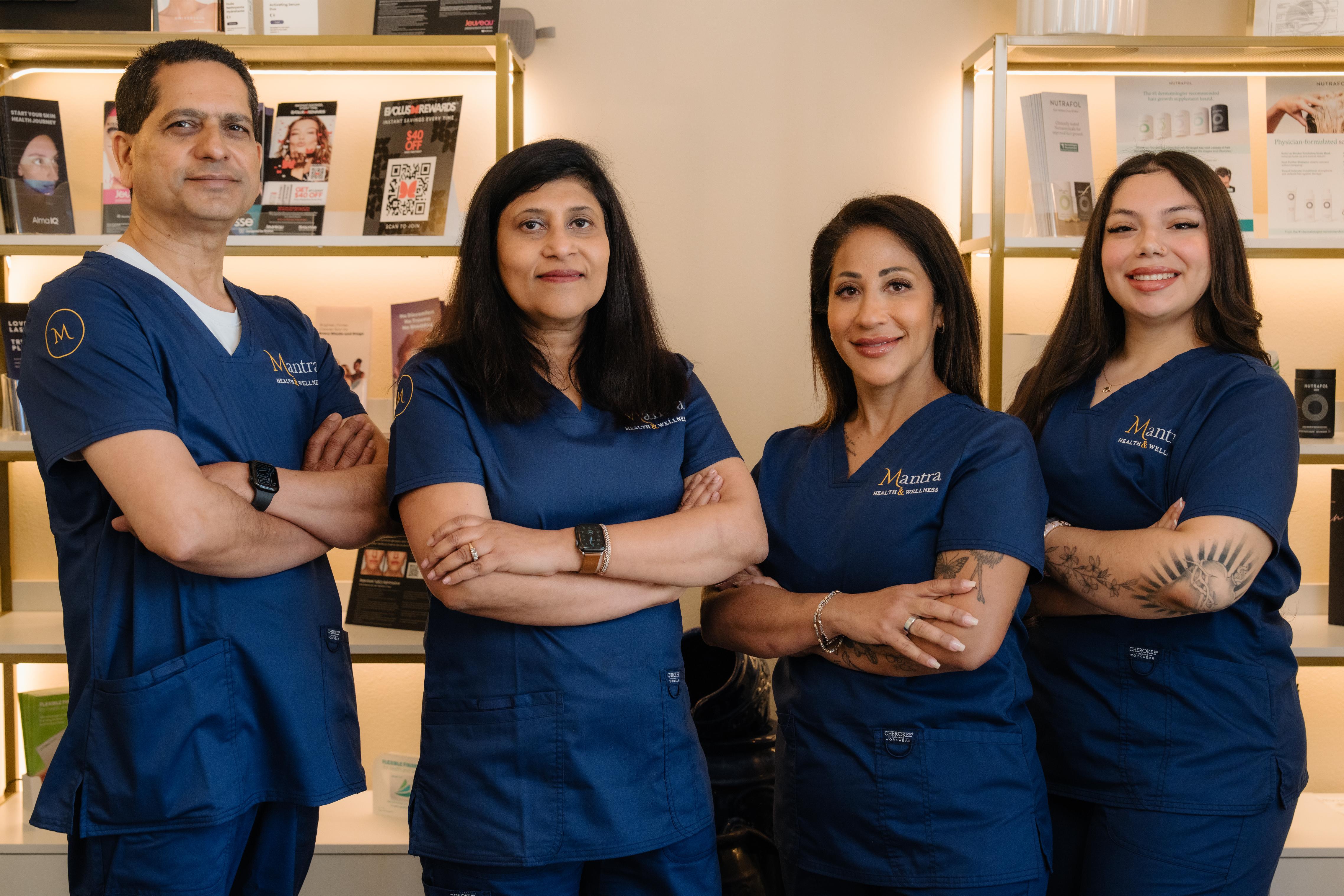 Four medical professionals in blue scrubs standing in a well-lit skincare clinic with product shelves.