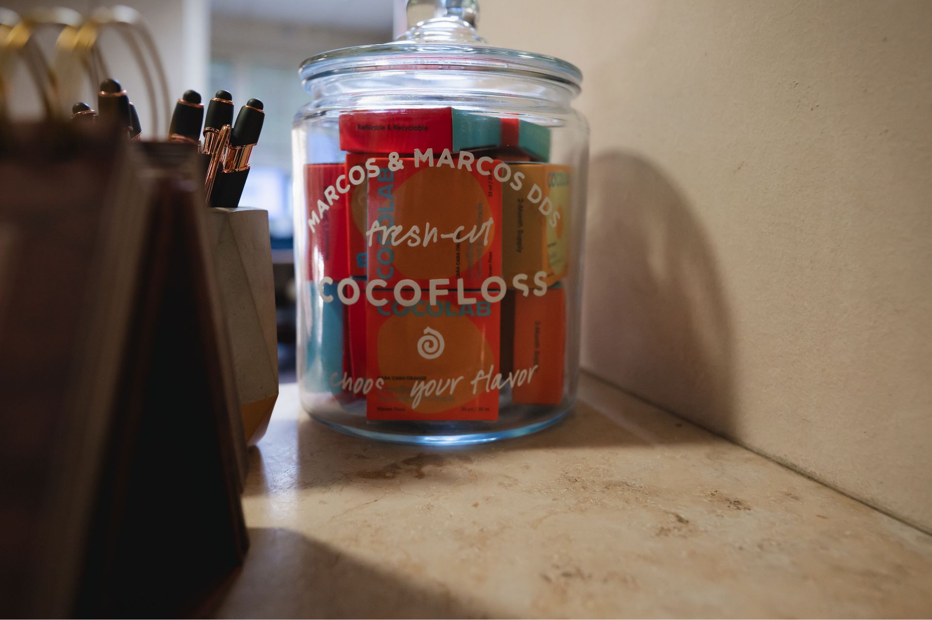 Glass jar labeled COCOLAB with colorful product boxes inside on a countertop.