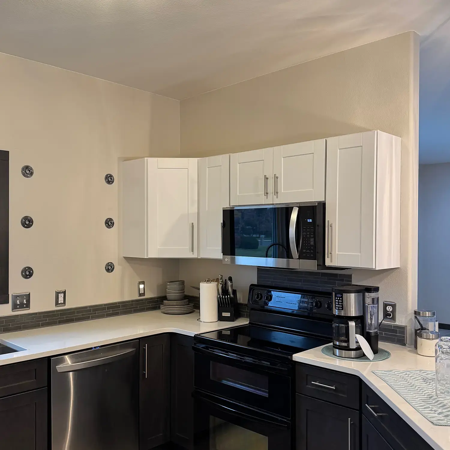 Refinished kitchen cabinets with white uppers and dark lower cabinets after professional cabinet painting
