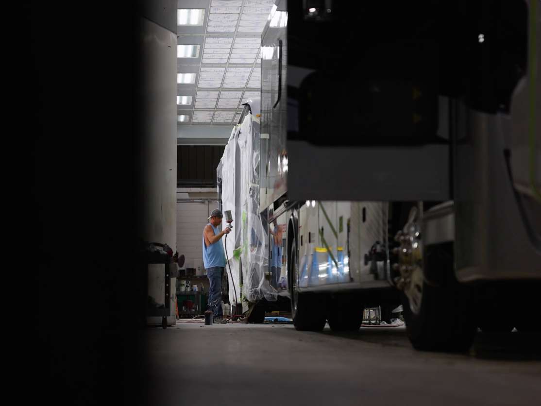 Cornerstone tech applying spray coating to the coach exterior