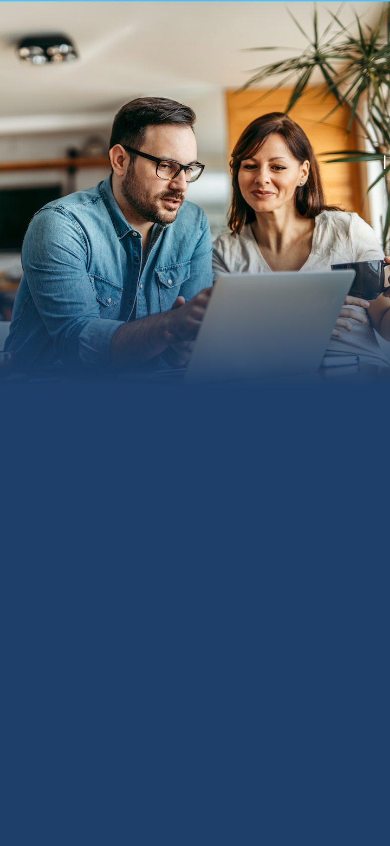 A man in glasses and a denim shirt and a woman holding a coffee cup work together on a laptop at a table.