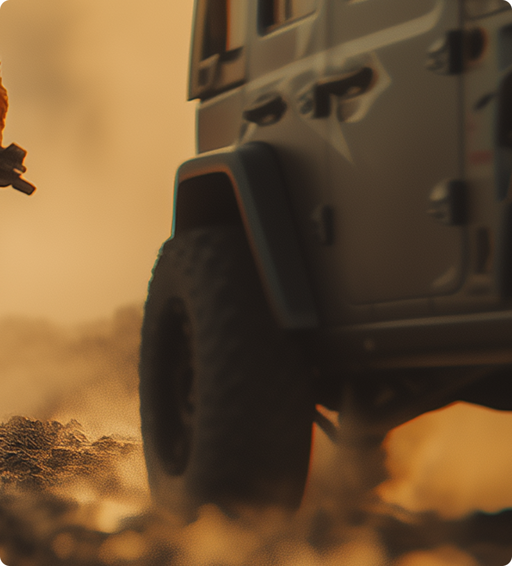 Close-up of an off-road vehicle tire driving on dusty terrain at sunset.