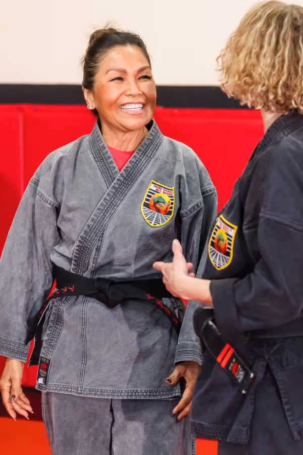 A young brown belt karate student practices a karate form using a fan as a weapon.