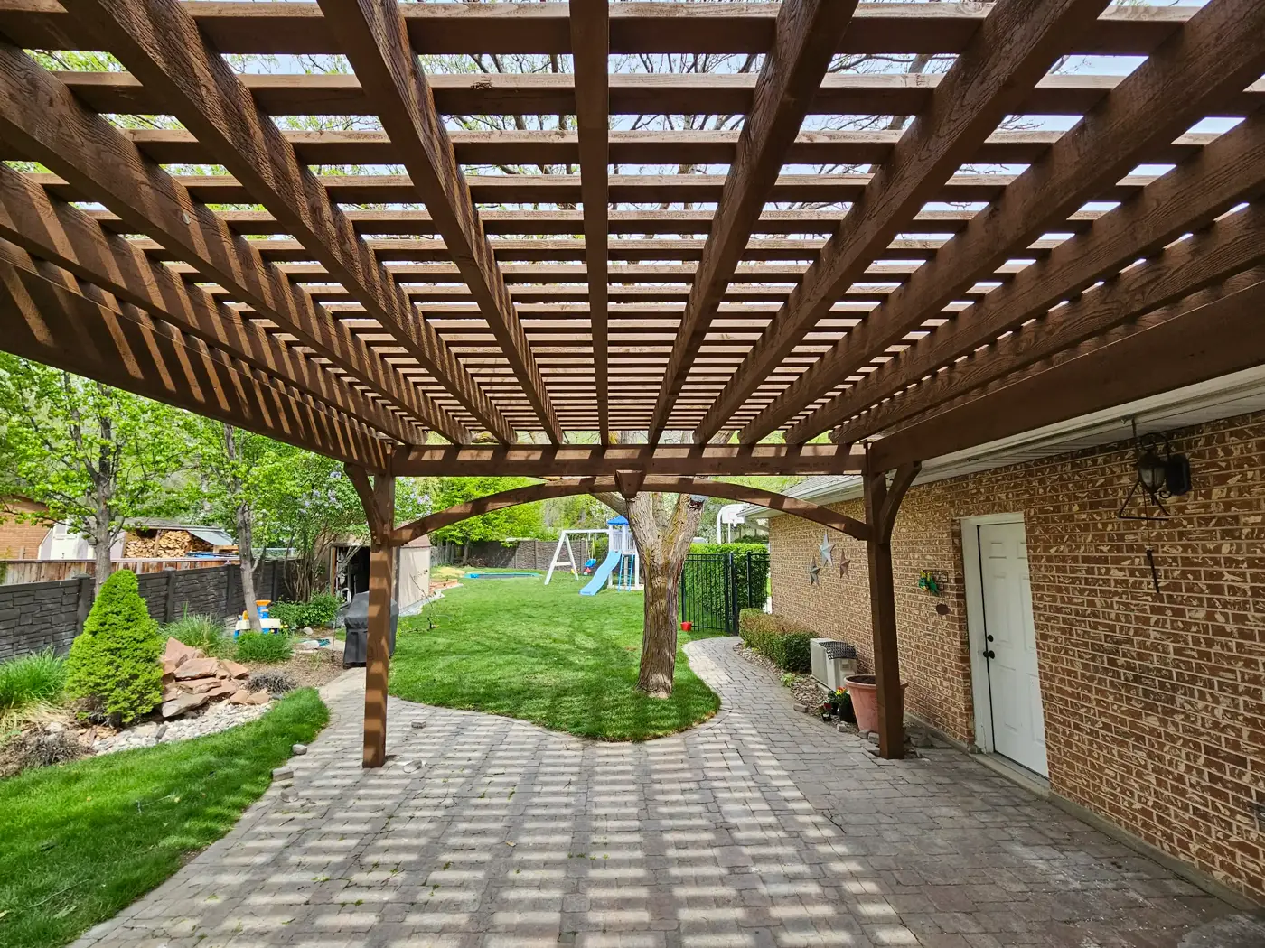 Grid-style timber pergola roof casting shadows on a paver patio