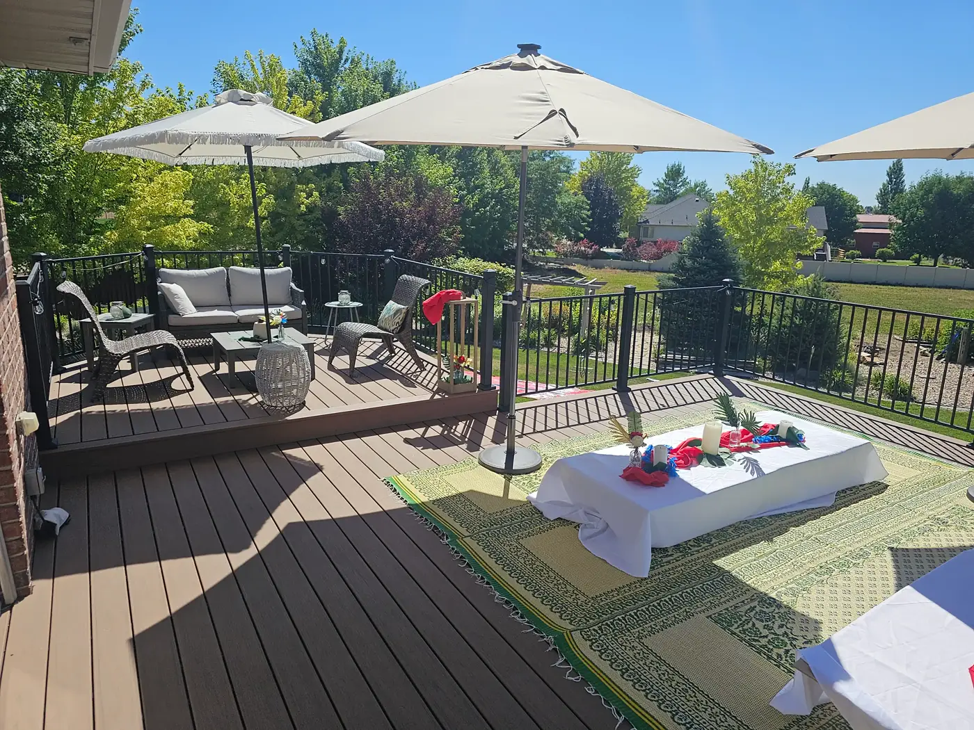 Open composite deck with patio umbrellas, seating and black railing