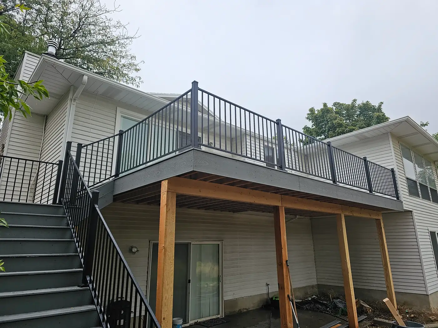 Elevated composite deck with black railing, stairs and cedar support posts