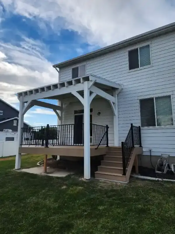 White pergola over a composite deck with black railing and stairs