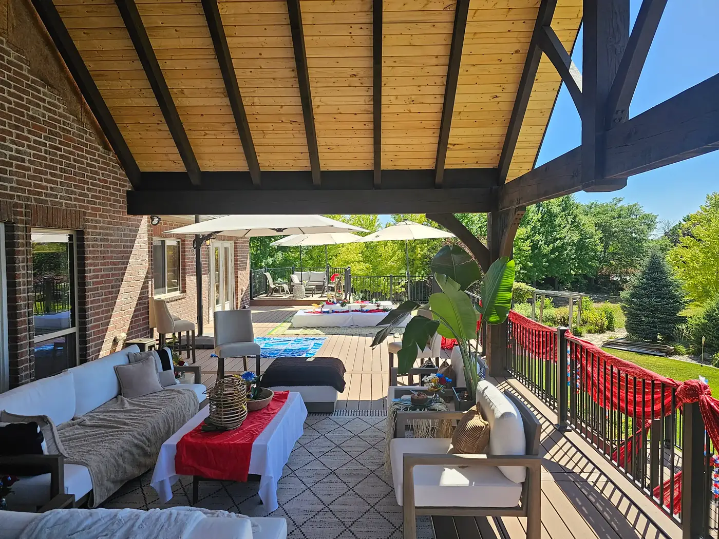 Covered deck lounge with seating under a timber gable and wood-plank ceiling