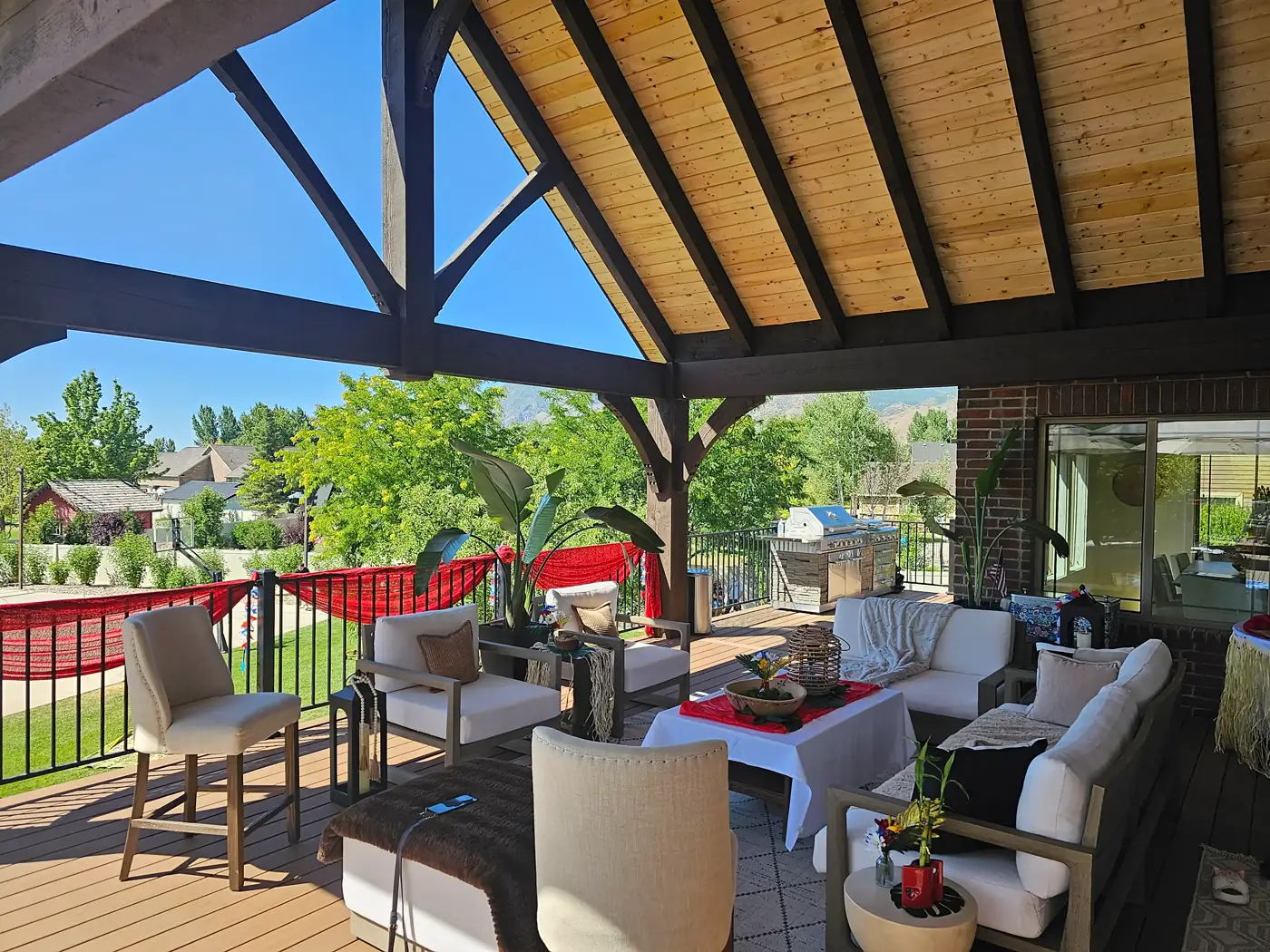 Covered deck seating area with an outdoor kitchen in the background