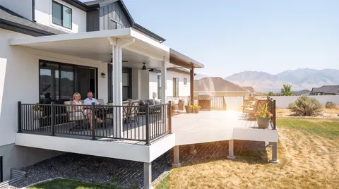 Covered deck with black railing and seating in the shade beside an open sunny deck