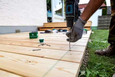 Gloved hand using a drill to fasten new decking boards