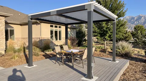 Freestanding louvered pergola over a patio dining set on composite decking