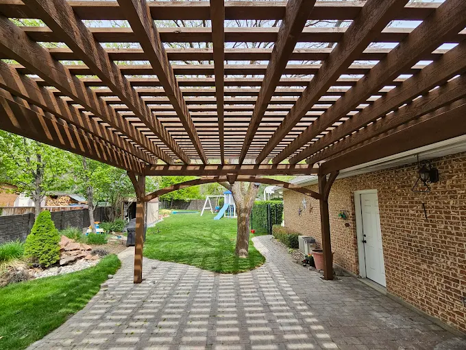 Timber lattice pergola over a paved path beside a brick home